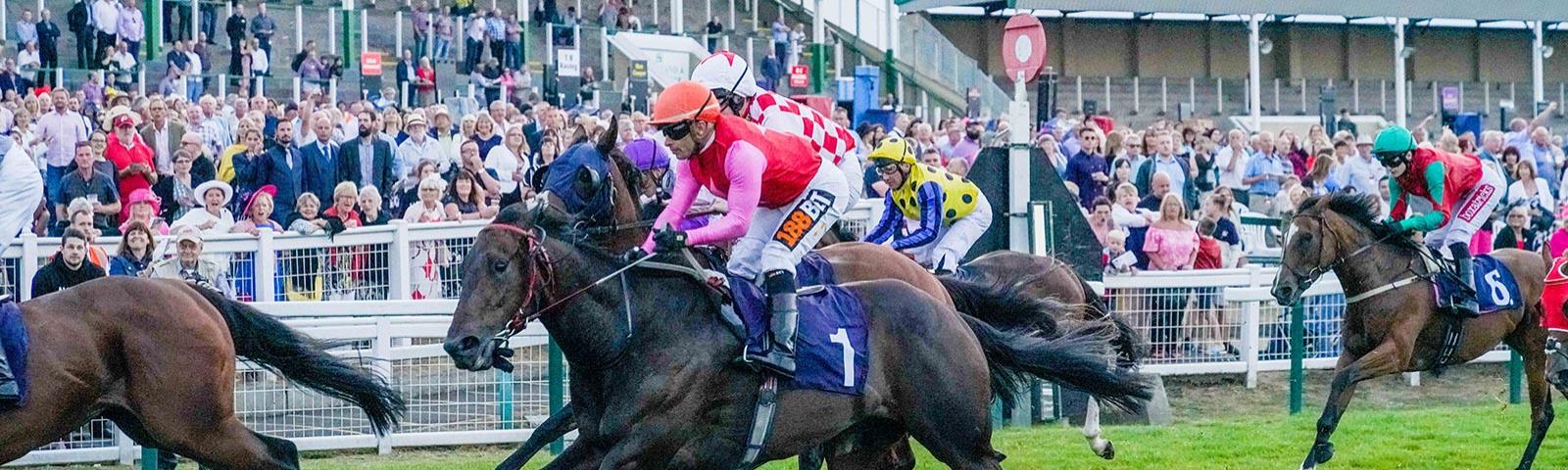 Group of jockeys racing past the finishing post at Great Yarmouth Racecourse.