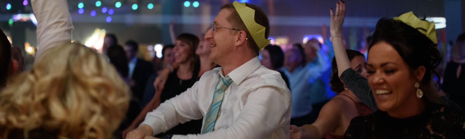Some Christmas Party guests in party hats dance to the disco.
