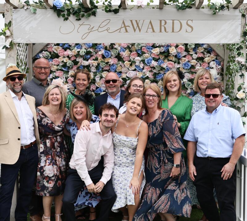 A group of friends poses in front of the flower wall at Great Yarmouth Races